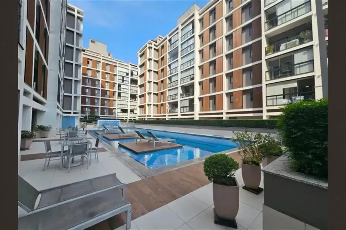 Fachada moderna do edifício Brise Clube Condomínio com varandas de vidro e paisagismo residencial.
