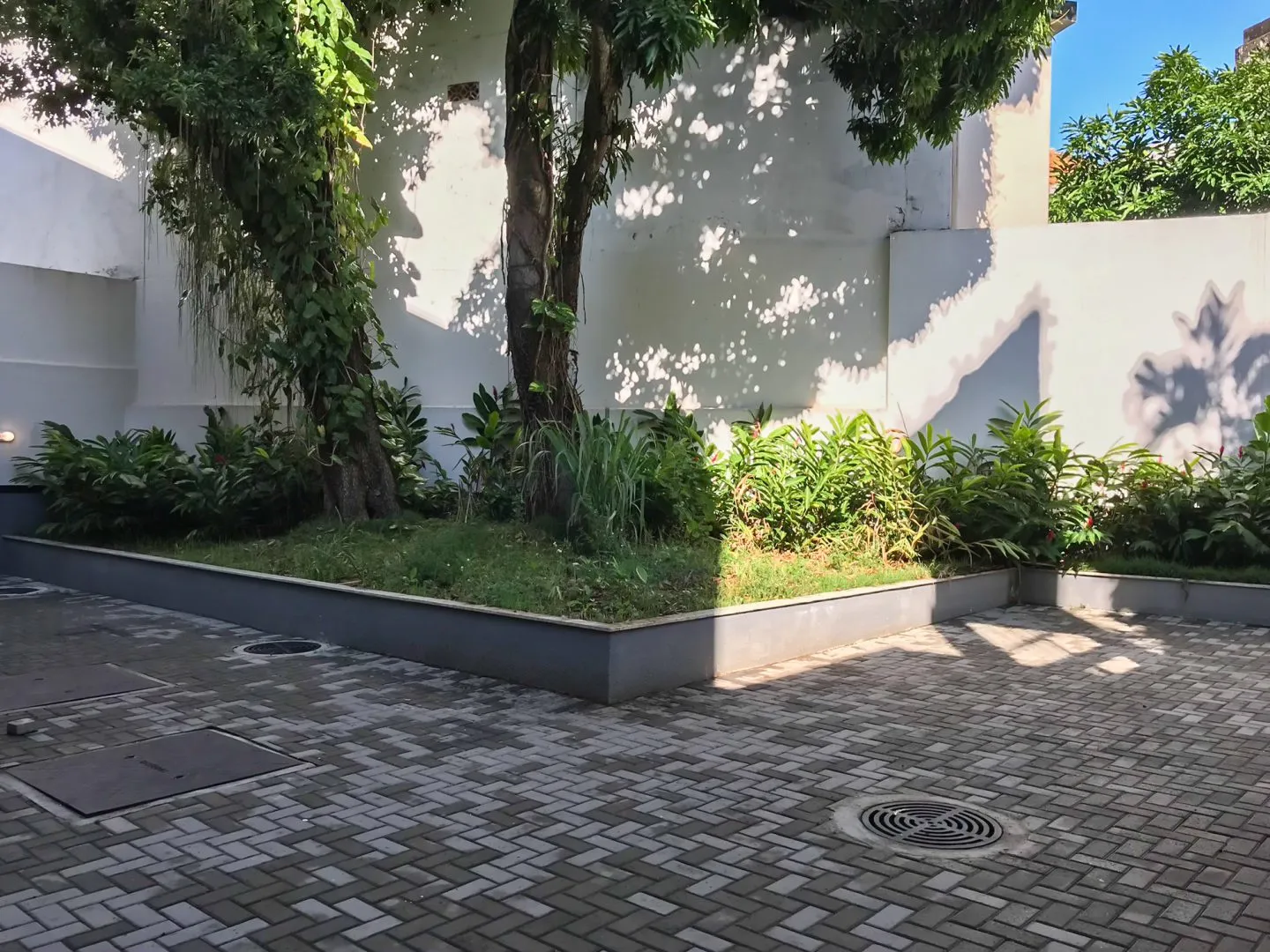 Edifício Di Iulio Urca, entorno arborizado com calçadas largas e comércio local.
