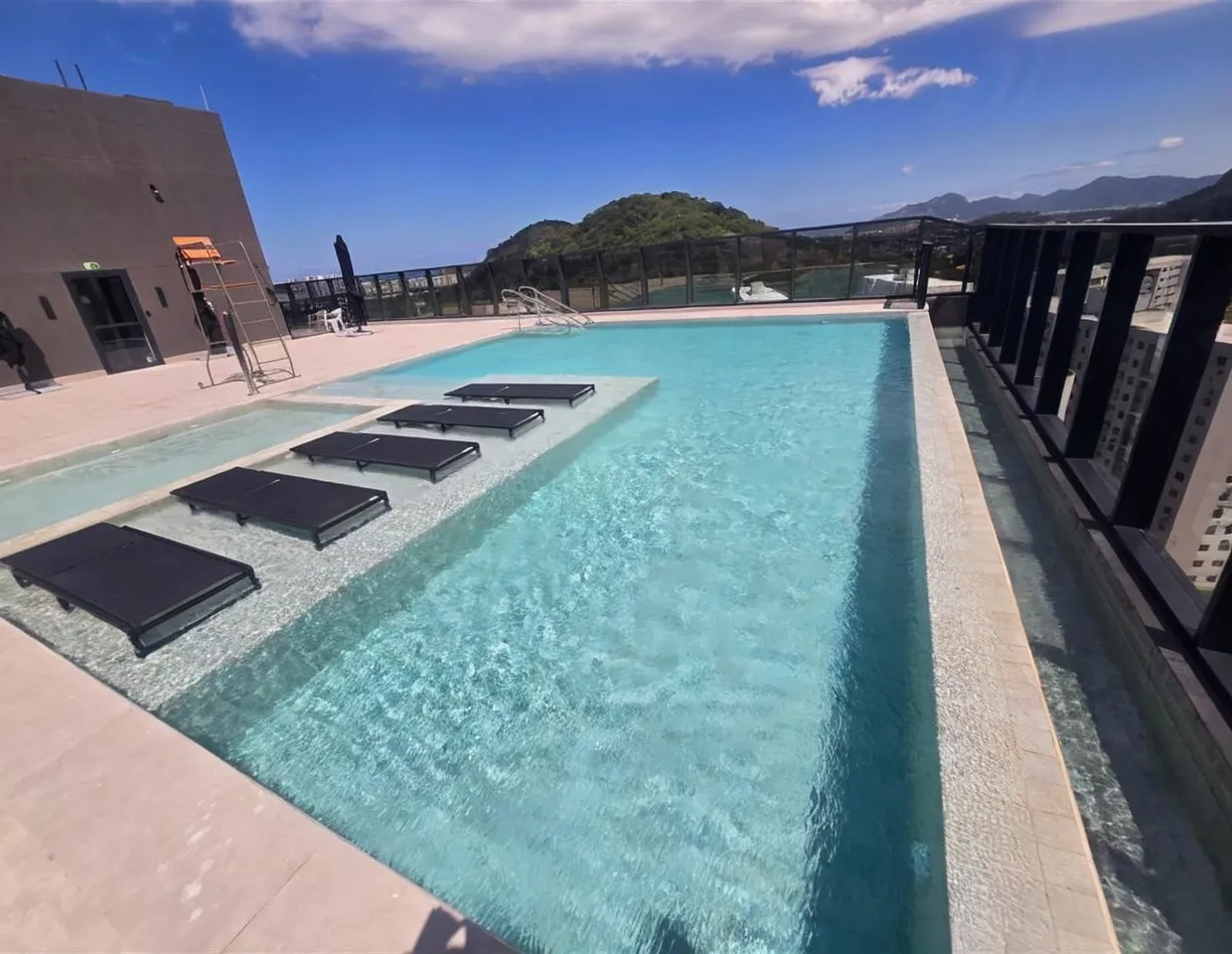 Varanda com fechamento de vidro: Varanda de apartamento com cortina de vidro instalada, bancada gourmet e vista para o condomínio.